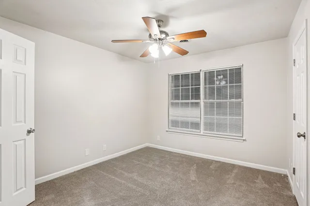 an empty room with window and ceiling fan