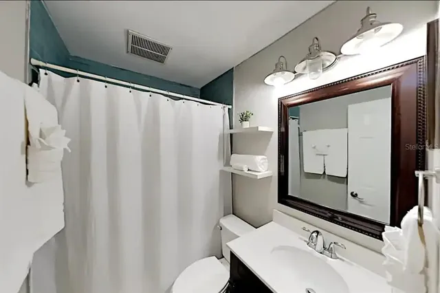 a bathroom with a sink and mirror with toilet