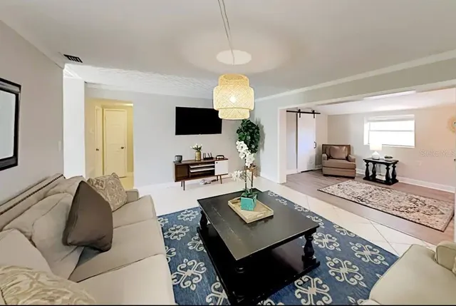 a living room with furniture a flat screen tv and a chandelier