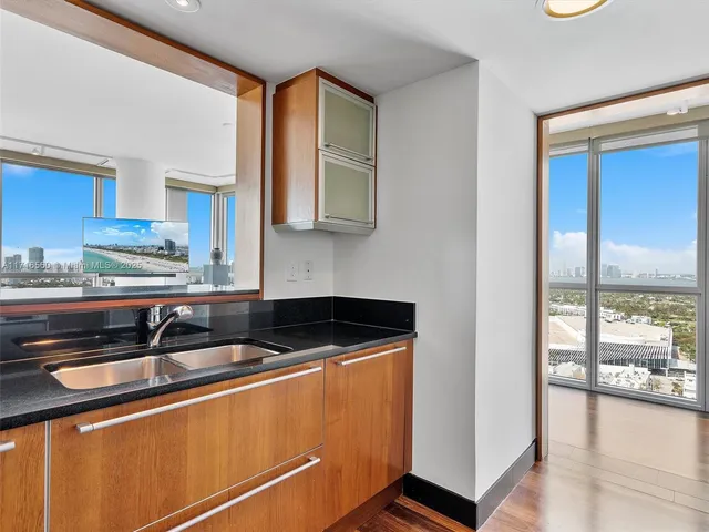 a kitchen with granite countertop a sink and a white wooden cabinets