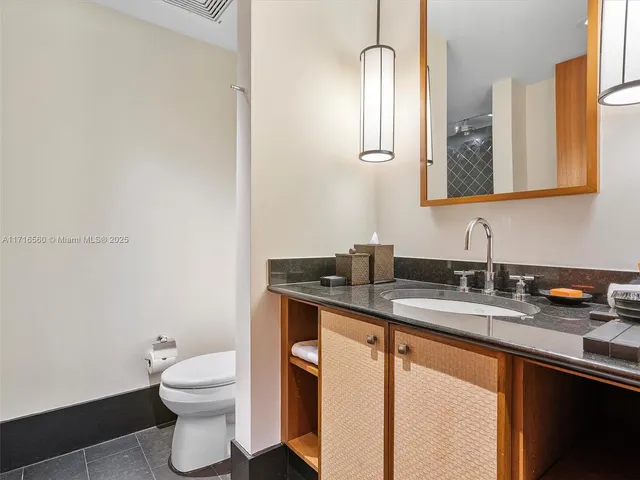 a bathroom with a granite countertop sink a toilet and a mirror