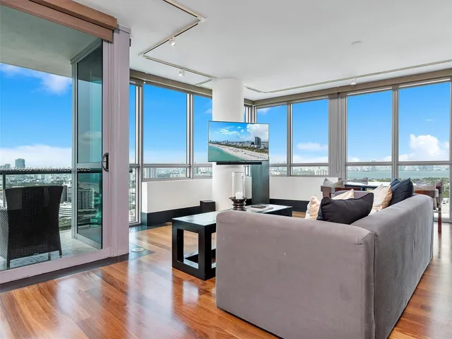a living room with furniture a fireplace and a floor to ceiling window