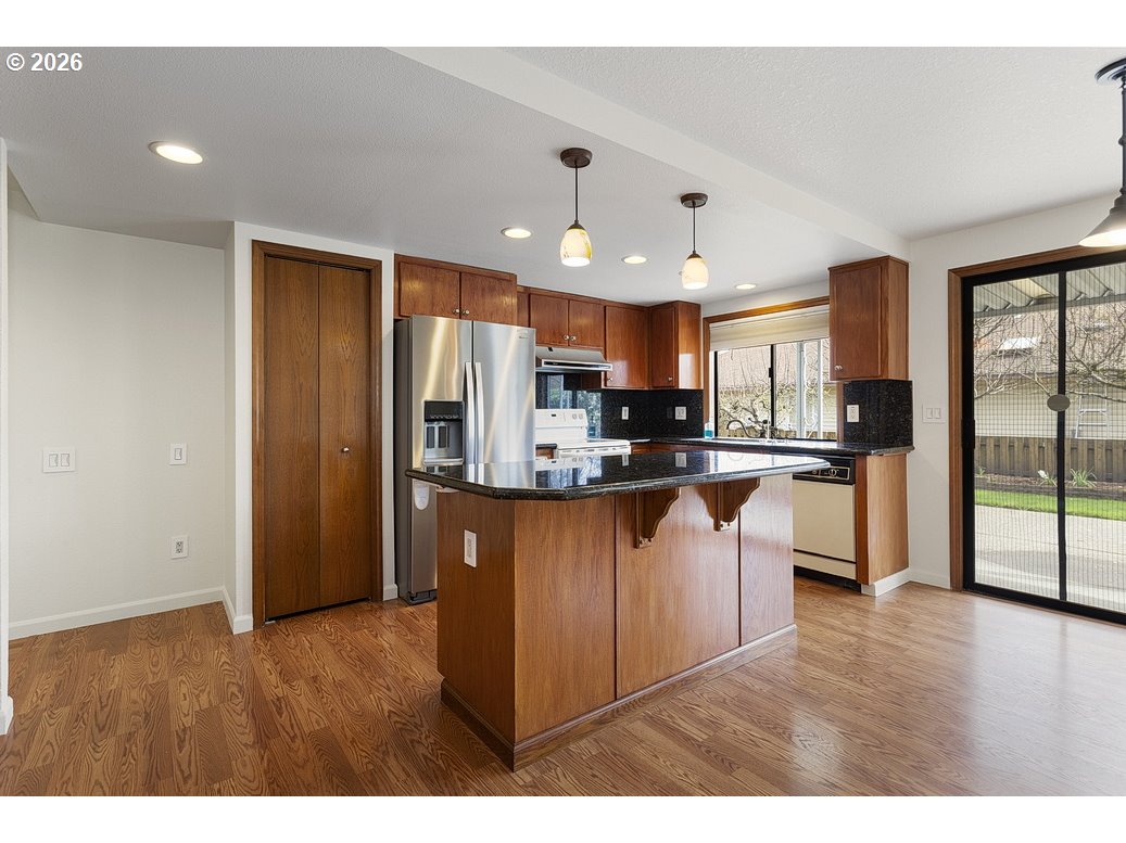 15638 Northeast Russell Place Portland, OR 97230 - Photo 17 of 46 a kitchen with stainless steel appliances granite countertop a refrigerator a sink dishwasher a stove with wooden cabinets and floor