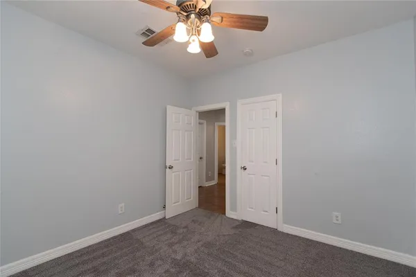 an empty room with a chandelier fan and closet area