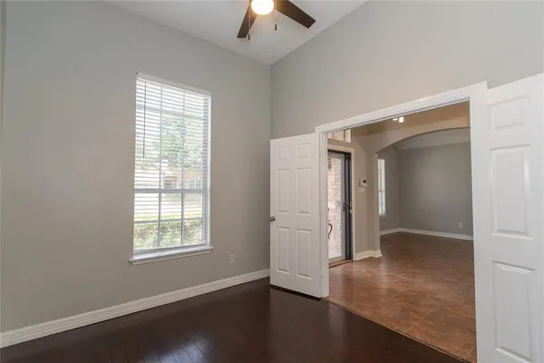 an empty room with wooden floor cabinet and windows