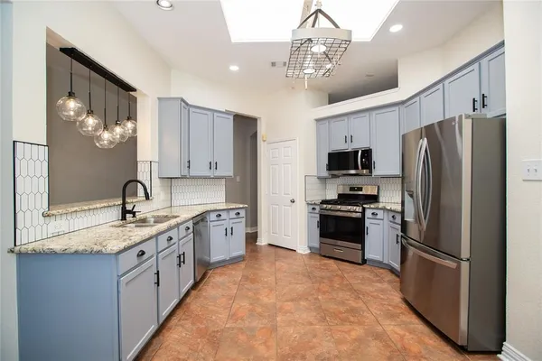 a kitchen with stainless steel appliances granite countertop a refrigerator a stove a sink and a microwave