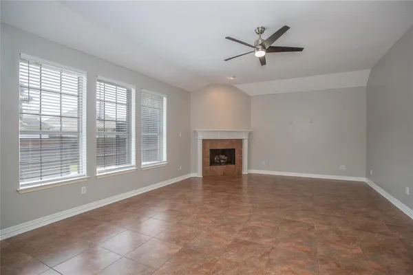 an empty room with ceiling fan and windows