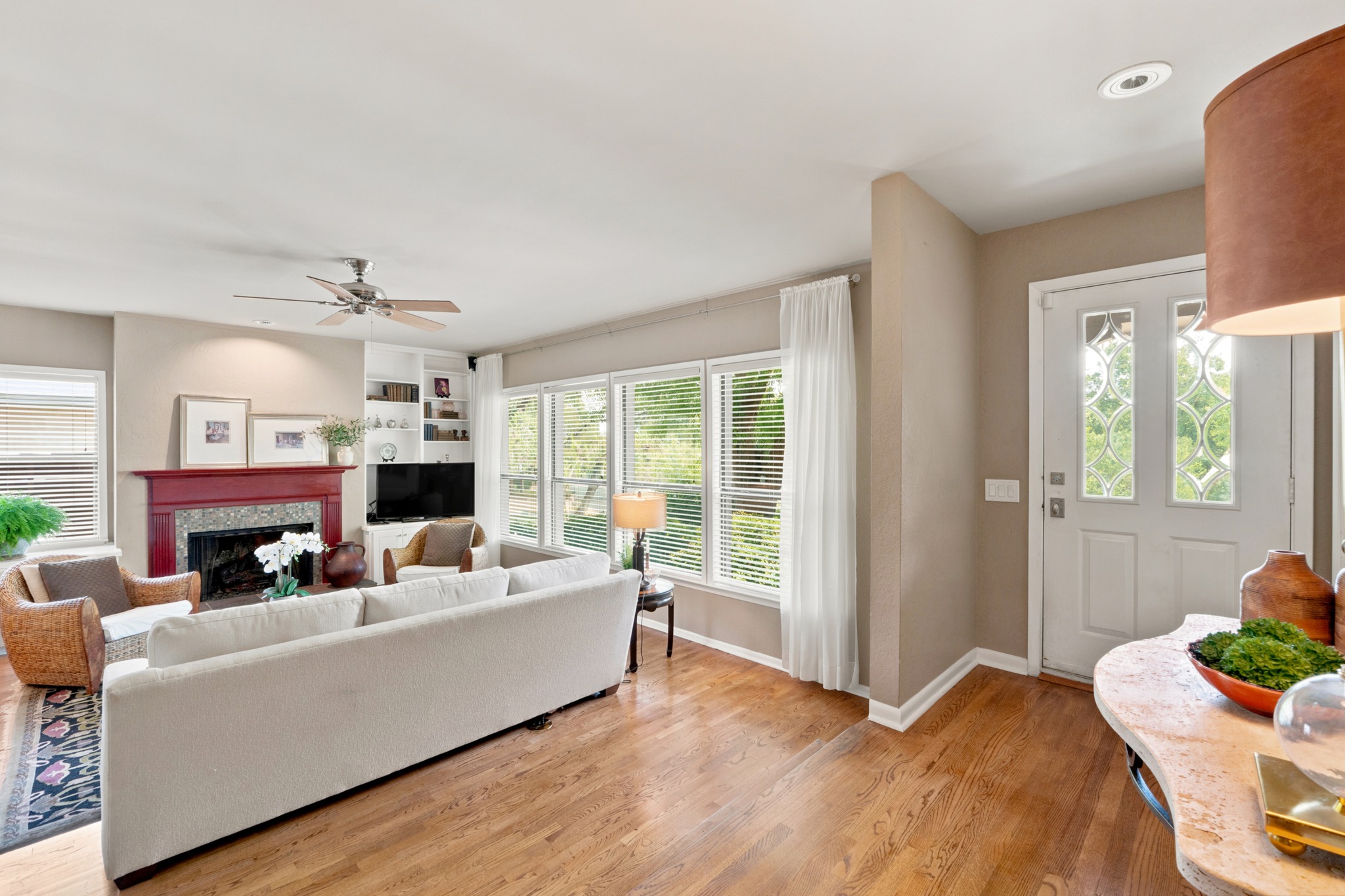 1904 Stoneridge Road Austin, TX 78746 - Photo 4 of 40 Light-filled living room features hardwood flooring, a fireplace and expansive windows overlooking the lush landscaping.