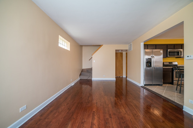 7609 Traube Street North Riverside, IL 60546 - Photo 2 of 25 an empty room with wooden floor kitchen view and windows