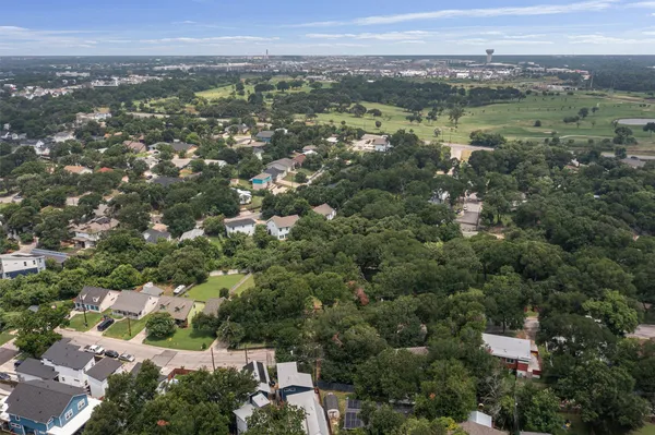 an aerial view of residential houses with outdoor space and trees