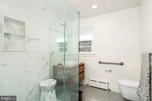 a bathroom with a granite countertop sink a toilet and shower
