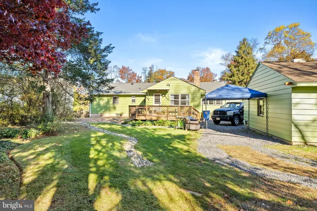 a view of a big house with table and chairs under an umbrella