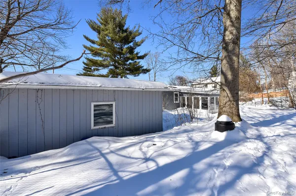a view of a wooden house with snow on the road