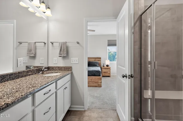 a spacious bathroom with a granite countertop sink a mirror and shower