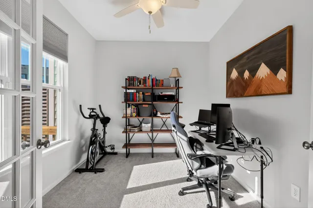 a view of a workspace with furniture and a ceiling fan