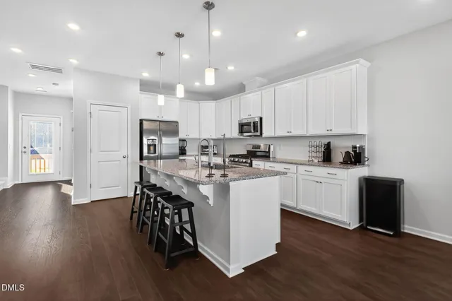 a kitchen with stainless steel appliances granite countertop a white cabinets and wooden floor