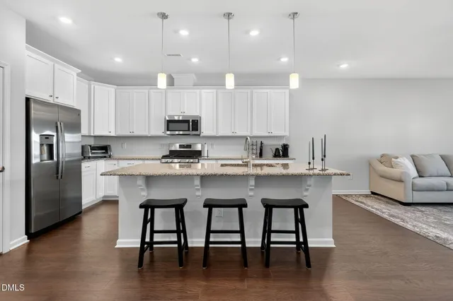 a kitchen with a refrigerator a stove a sink and a dining table with wooden floor