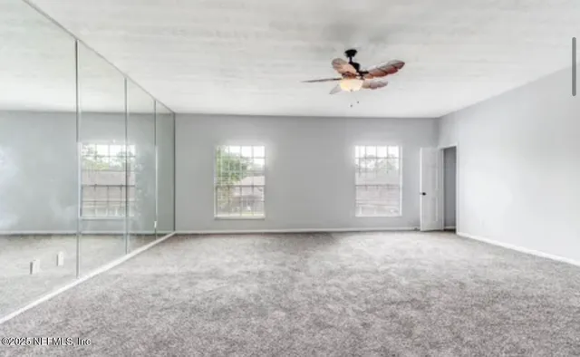 an empty room with windows and fan