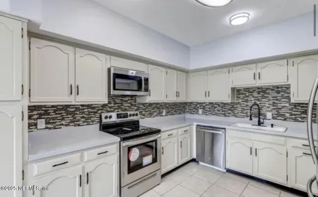 a kitchen with white cabinets sink and stainless steel appliances
