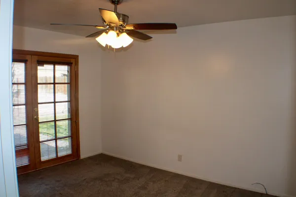 an empty room with windows and chandelier fan