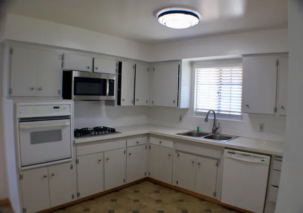 a kitchen with cabinets appliances a sink and a window
