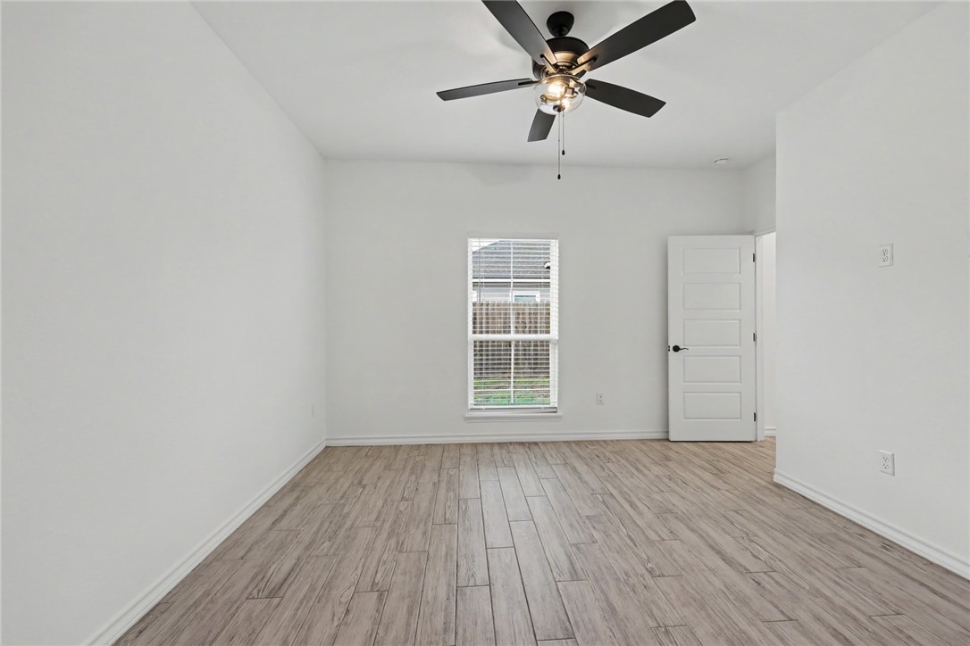 143 Amethyst Street Portland, TX 78374 - Photo 21 of 26 an empty room with wooden floor ceiling fan and windows
