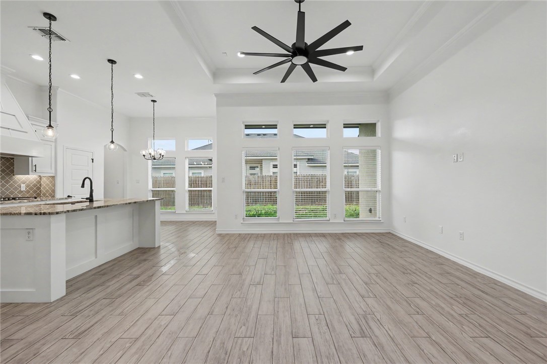 143 Amethyst Street Portland, TX 78374 - Photo 5 of 26 a view of an empty room with a kitchen and wooden floor