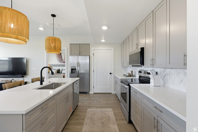 961 West Akoya Pearl Road, Unit 300 St. George, UT 84790 - Photo 2 of 60 Dual tone kitchen featuring stainless steel appliances, an island with sink, hanging light fixtures, light wood-type flooring, and light stone counters