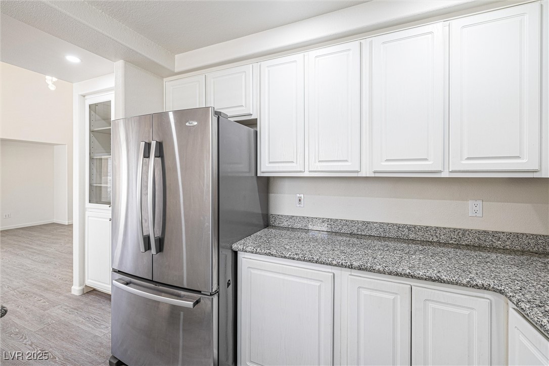 10133 Rice Paper Street Las Vegas, NV 89183 - Photo 15 of 36 Kitchen with freestanding refrigerator, white cabinetry, wood finished floors, light stone countertops, and a new recessed ceiling with LED lights