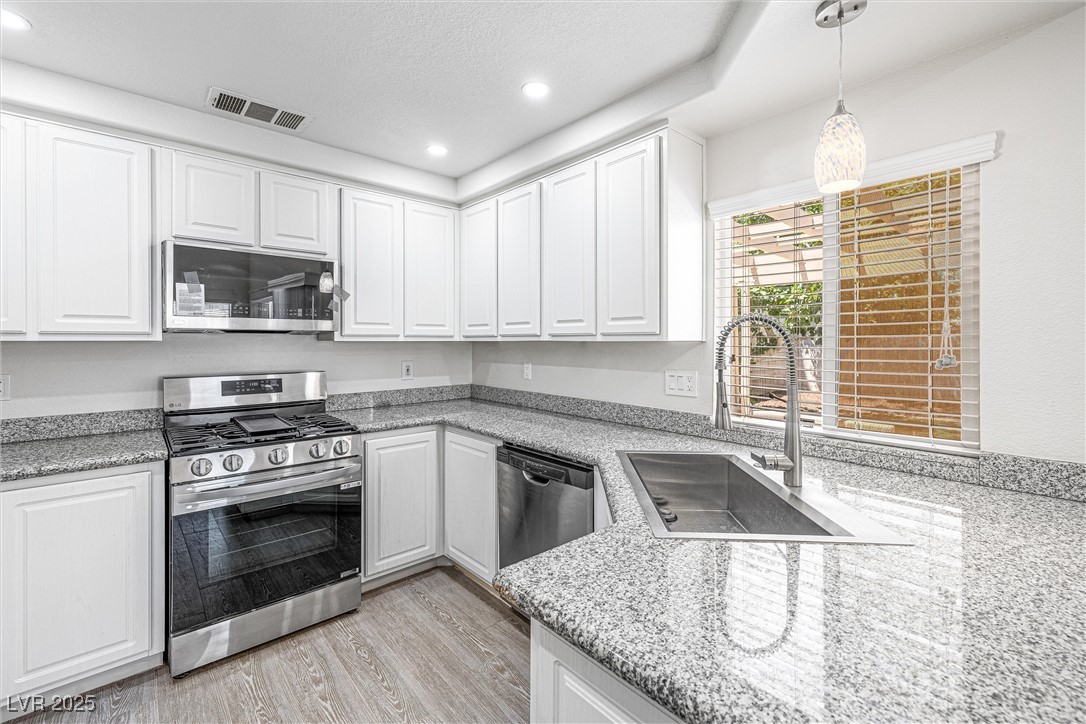 10133 Rice Paper Street Las Vegas, NV 89183 - Photo 17 of 36 Kitchen featuring Granite Countertops+ NEW appliances with stainless steel finishes, light wood-style flooring, white cabinets, recessed lighting, and decorative light fixtures