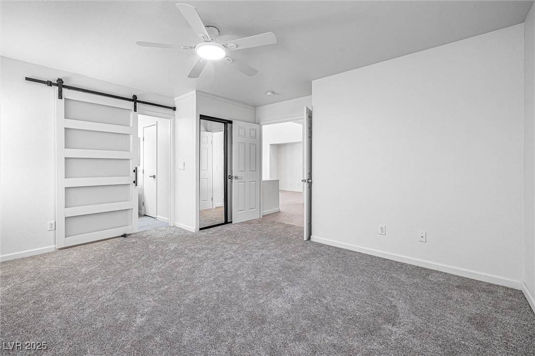 10133 Rice Paper Street Las Vegas, NV 89183 - Photo 20 of 36 NEW carpet flooring, a barn door, and a ceiling fan