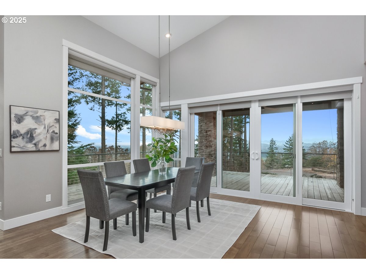 32047 Northeast Corral Creek Road Newberg, OR 97132 - Photo 7 of 40 a dining room with furniture large windows and wooden floor