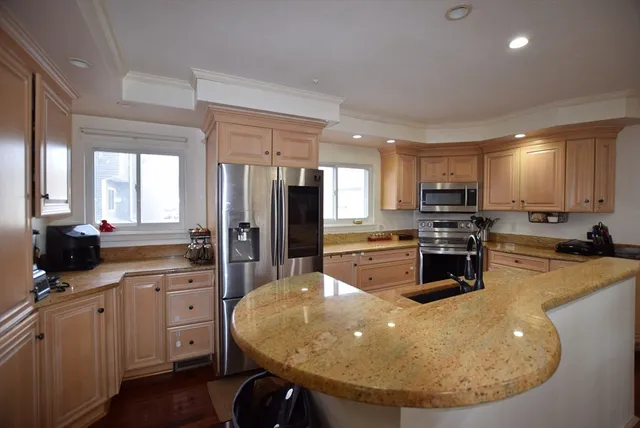 a kitchen with stainless steel appliances granite countertop a sink a stove a refrigerator a center island and cabinets