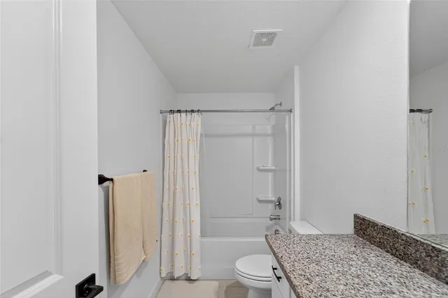 a bathroom with a granite countertop sink a toilet and shower