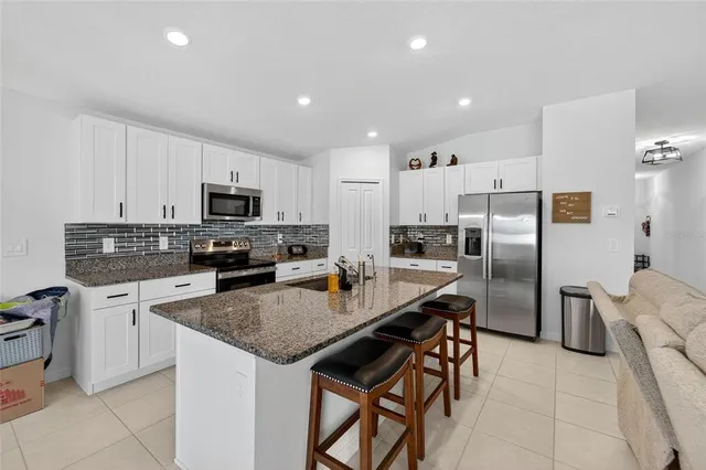 a kitchen with stainless steel appliances granite countertop a stove a sink a microwave a refrigerator and cabinets