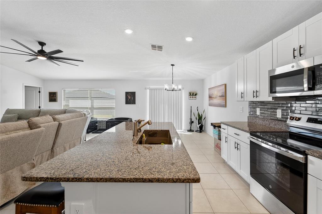 13073 Garnet Raspberry Avenue Wimauma, FL 33598 - Photo 33 of 50 a kitchen with stainless steel appliances granite countertop a sink a stove and cabinets