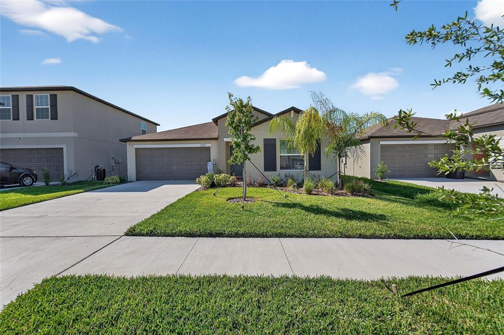 13073 Garnet Raspberry Avenue Wimauma, FL 33598 - Photo 5 of 50 a view of a white house with a yard and potted plants
