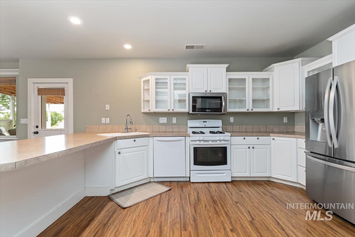 10462 West Lanktree Gulch Road Star, ID 83669 - Photo 29 of 48 Expansive kitchen featuring wood-finish flooring, white cabinetry, and light-toned countertops