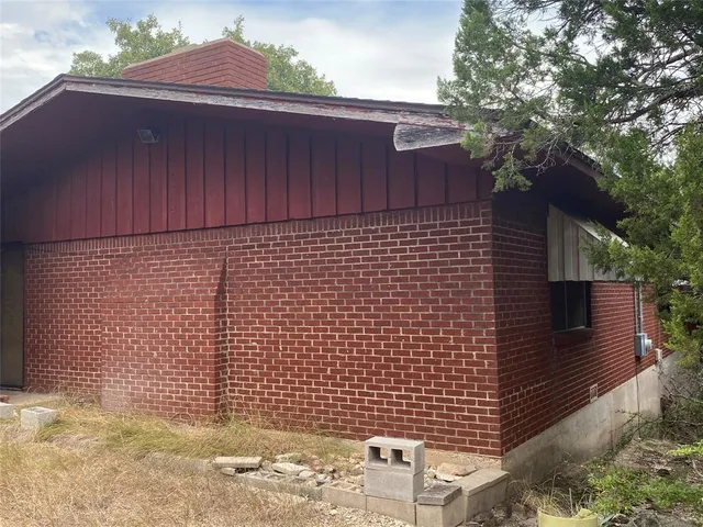 a backyard of a house with table and chairs under an umbrella
