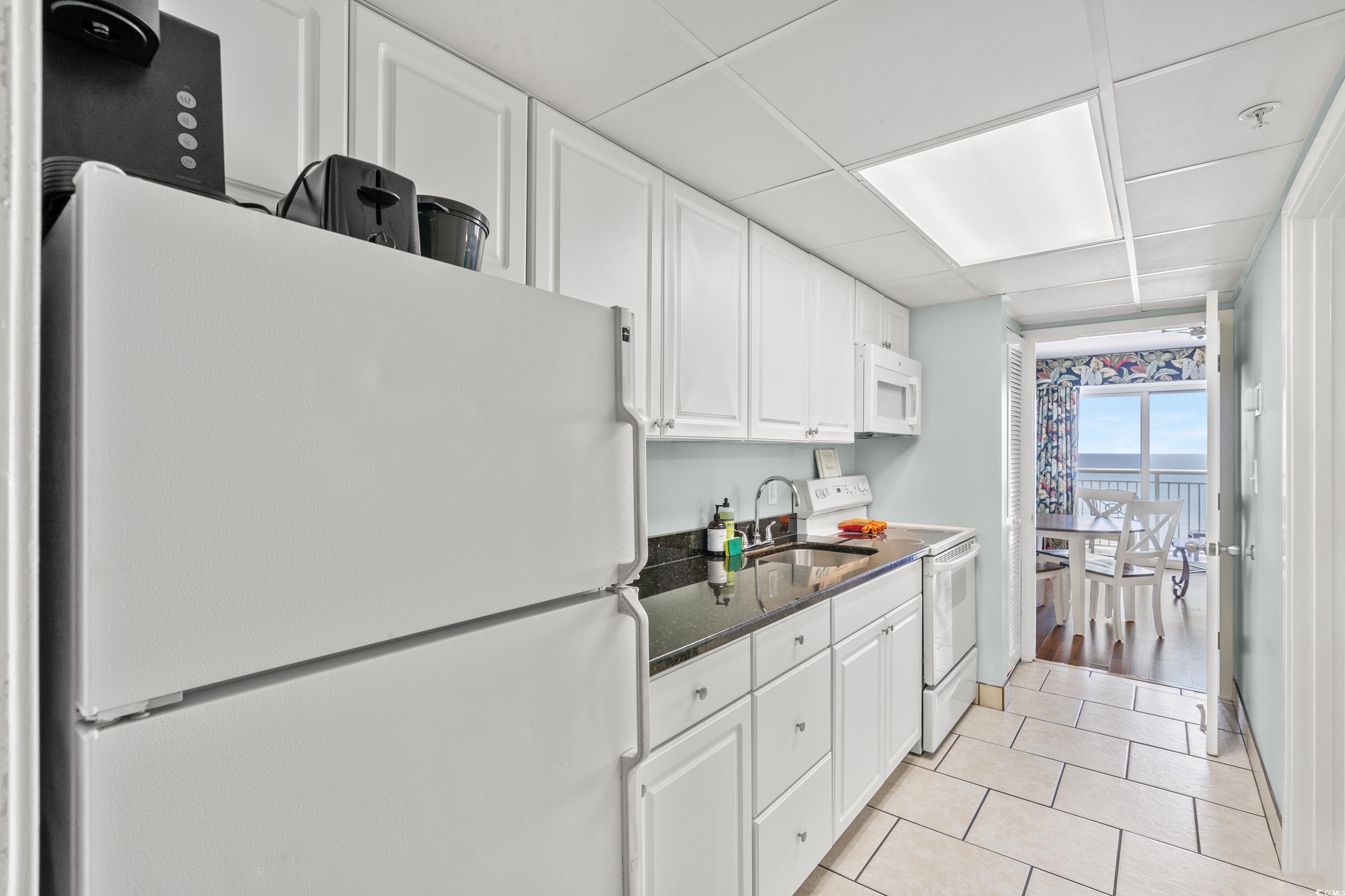 2000 North Ocean Boulevard, Unit 1612 Myrtle Beach, SC 29577 - Photo 4 of 21 Kitchen featuring sink, light tile patterned floors, white appliances, and white cabinetry