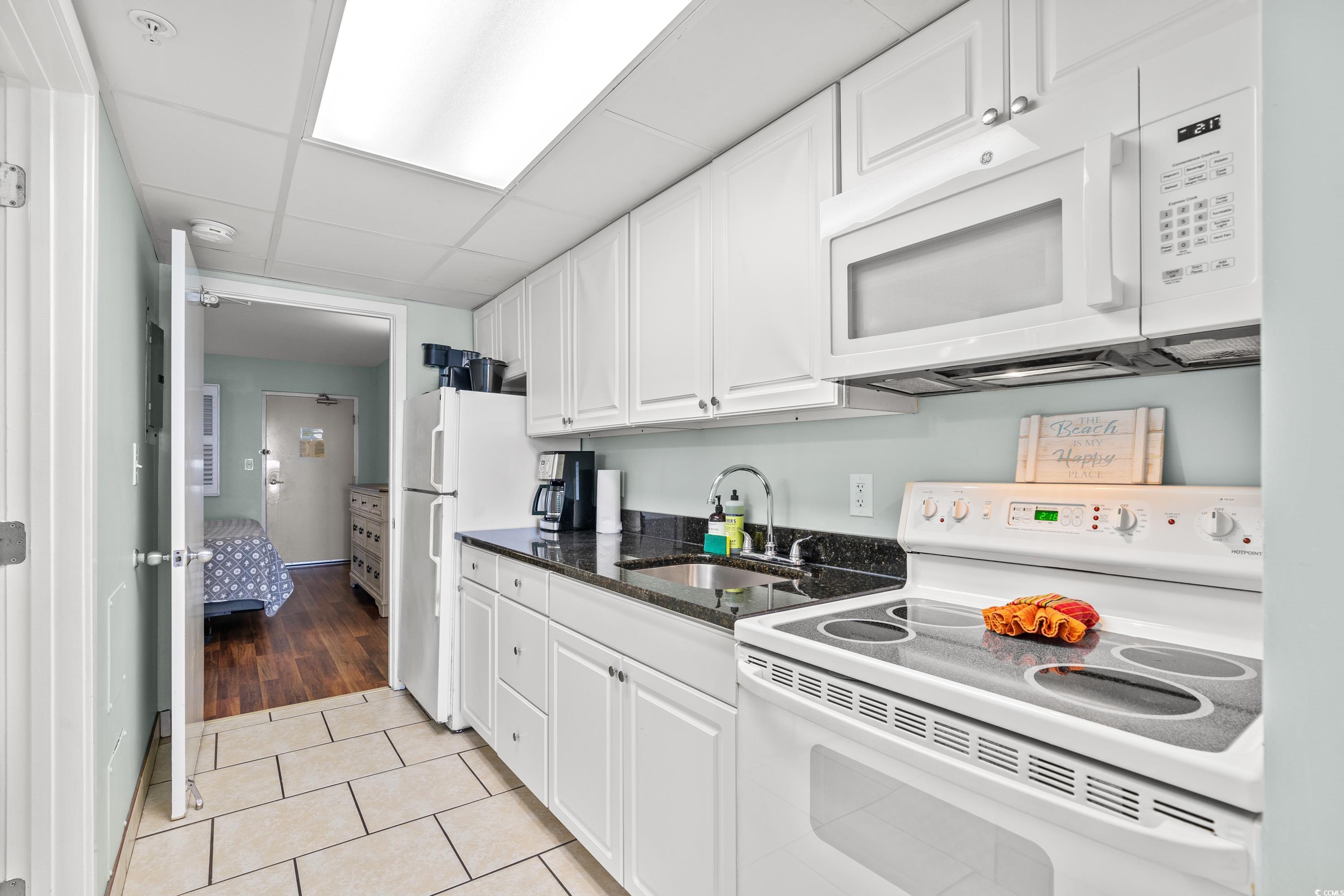 2000 North Ocean Boulevard, Unit 1612 Myrtle Beach, SC 29577 - Photo 5 of 21 Kitchen with light wood-type flooring, white appliances, white cabinetry, sink, and a drop ceiling