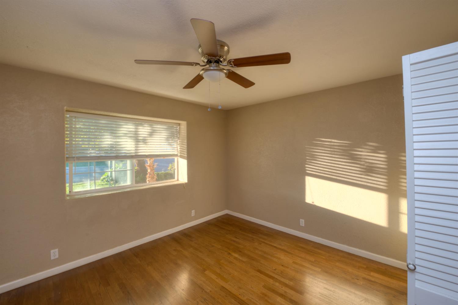 902 Waller Street Gustine, CA 95322 - Photo 22 of 32 a view of an empty room with wooden floor and a window