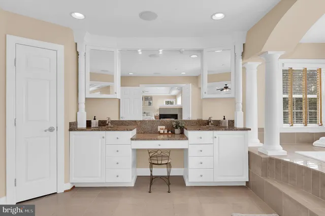 a large white kitchen with kitchen island a large window a sink and cabinets