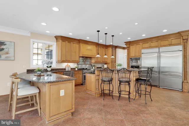 a kitchen with stainless steel appliances kitchen island granite countertop a stove a refrigerator a sink a dining table and chairs with wooden floor
