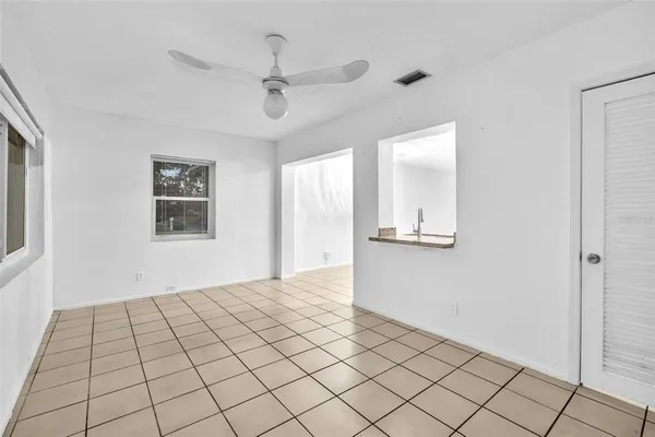 a view of an empty room with window and chandelier fan