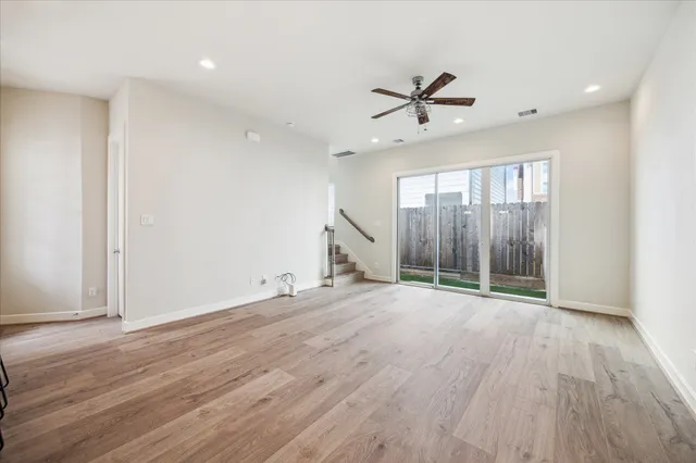 an empty room with wooden floor fan and windows