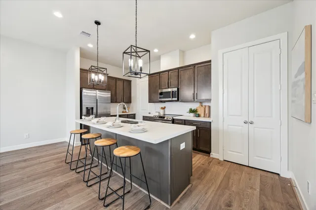 a kitchen with kitchen island stainless steel appliances a table chairs sink and wooden floor