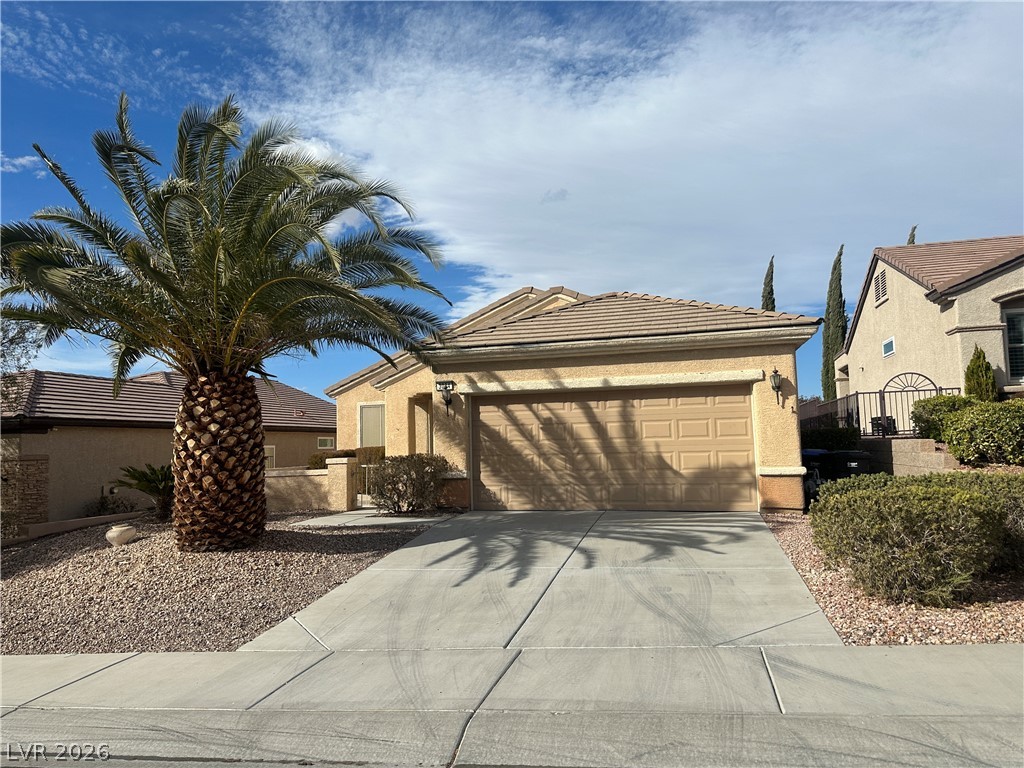 This desert-landscaped home features a functional attached garage and a concrete driveway.