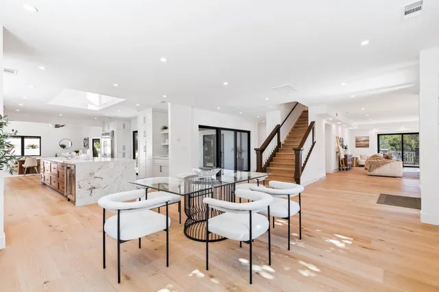 a large kitchen with kitchen island a stove a sink a refrigerator and a dining table with wooden floor