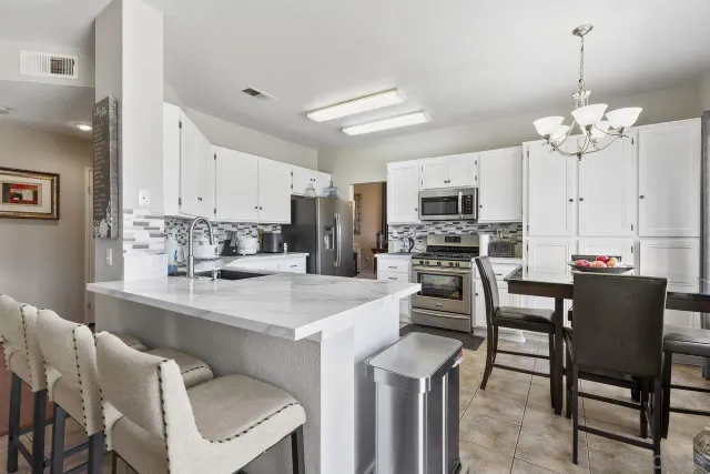 a view of kitchen with cabinets stainless steel appliances and a dining table